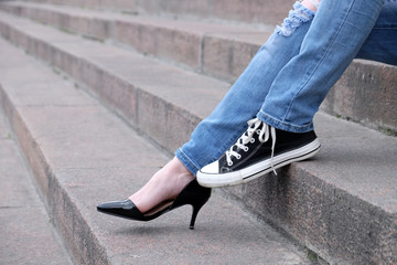 Fototapeta na wymiar Female feet in different shoes on stone stairs