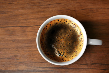 Cup of fresh coffee on wooden table, top view
