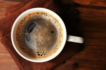 Cup of fresh coffee with beans on table, closeup