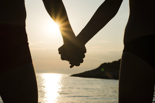 Couple on a beach holding hands at sunset