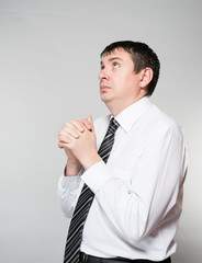 portrait of a young businessman praying on a gray background