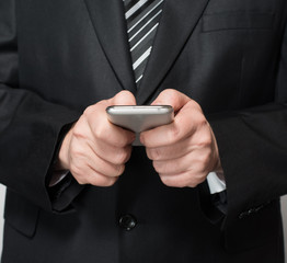 Young businessman sending message with mobile phone