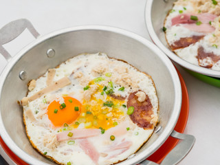 Fried eggs with pork in pan.