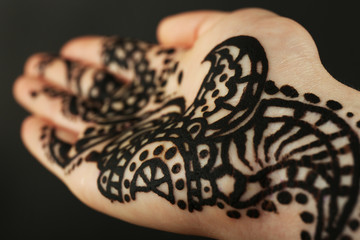 Fototapeta na wymiar Closeup image of henna on female hand on dark background