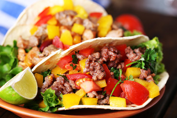 Homemade beef burritos with vegetables on plate, on wooden background