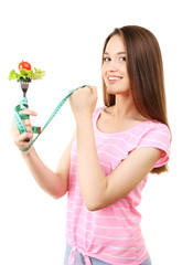 Healthy young woman with vegetables on fork and measuring tape isolated on white