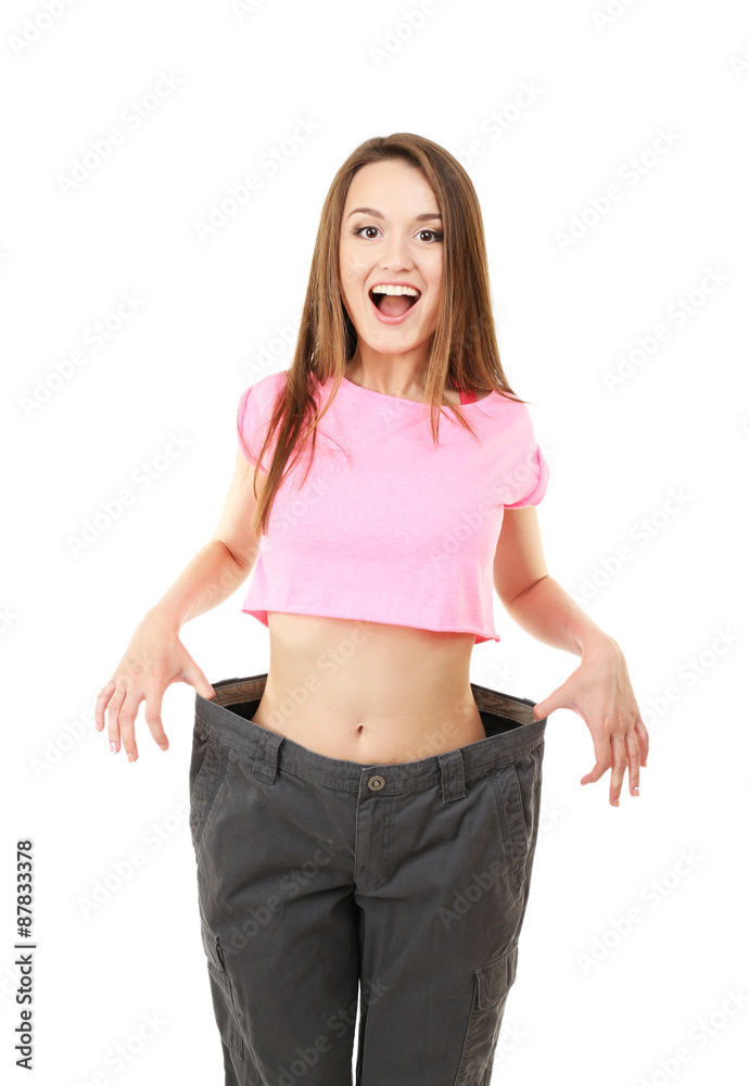 Wall mural Young slim woman wearing too big pats isolated on white