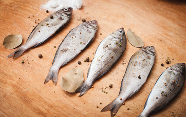 fresh raw fishes with spices on a cutting wooden board
