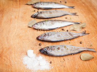 fresh raw fishes with spices on a cutting wooden board