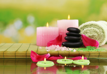 Spa still life with pink petals and candlelight on green blurred background