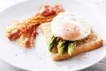 Dish of asparagus and egg in plate on table, closeup