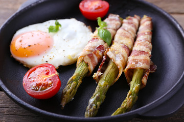 Dish of asparagus with eggs and bacon in pan on table, closeup
