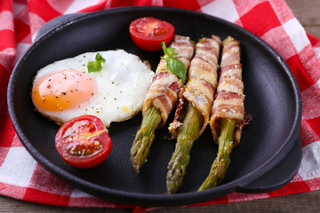 Dish of asparagus with eggs and bacon in pan on table, closeup