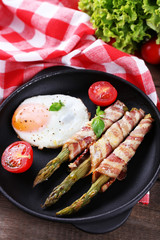 Dish of asparagus with eggs and bacon in pan on table, closeup