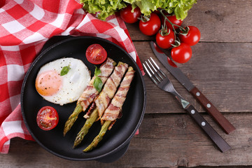 Dish of asparagus with eggs and bacon in pan on table, top view