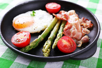 Dish of asparagus with eggs and bacon in pan on table, closeup