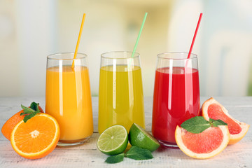 Naklejka na ściany i meble Glasses of different juice with fruits and mint on bright background