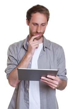 Moderner junger Mann mit Bart liest E-Book am Tablet