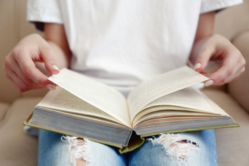 Woman reading book on sofa close up