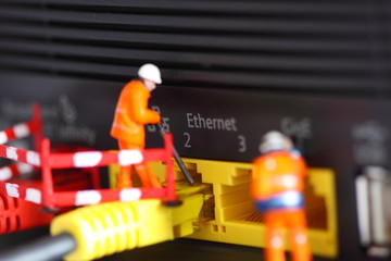 Miniature construction workers router.
Miniature scale model construction workers connecting cable to a router.