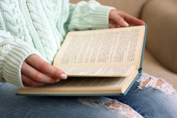 Fototapeta premium Woman reading book on sofa close up