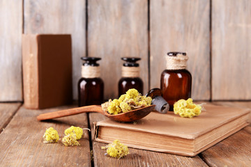 Old books with dry flowers and bottles on wooden background