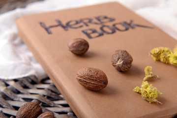 Dried herb with nutmeg and book on table close up