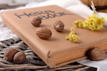 Dried herb with nutmeg and book on table close up