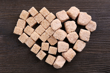 Sugar cubes in heart shape on wooden background