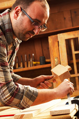 Closeup of a carpenter working with a hammer, chisel and wood carving tools.