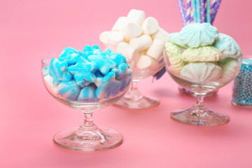 Fluffy candies in glassware on pink background