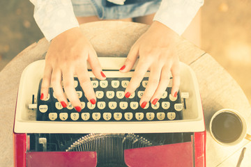 woman typing on a typewriter with cup of coffee