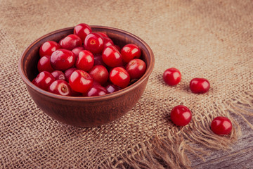 Cherries in brown bowl on burlap background.