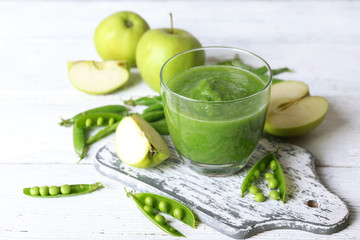Healthy green smoothie with peas and apples on wooden table, closeup