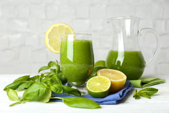 Healthy green smoothie on wooden table on white wall background