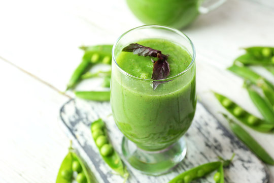 Healthy green smoothie with peas on wooden table, closeup
