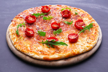 Pizza with arugula and cherry tomatoes on wooden background