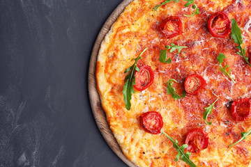 Pizza with arugula and cherry tomatoes on wooden background