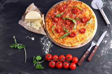 Pizza with arugula and cherry tomatoes on wooden background