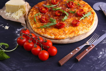 Pizza with arugula and cherry tomatoes on wooden background