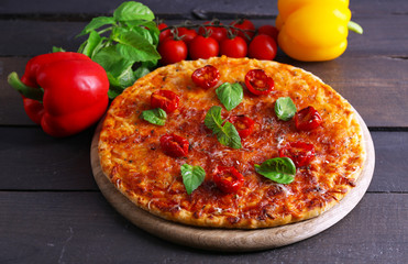 Pizza with basil and cherry tomatoes on wooden table, closeup