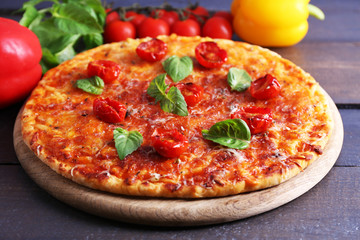Pizza with basil and cherry tomatoes on wooden table, closeup
