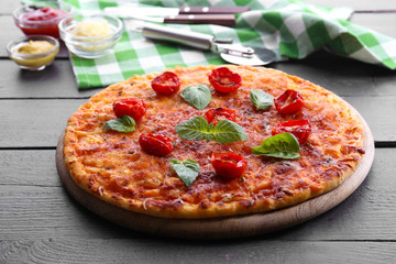 Pizza with basil and cherry tomatoes on wooden table, closeup