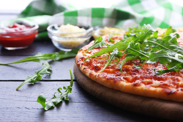 Pizza with arugula on wooden table, closeup
