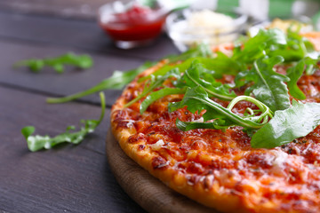 Pizza with arugula on wooden table, closeup