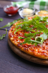Pizza with arugula on wooden table, closeup