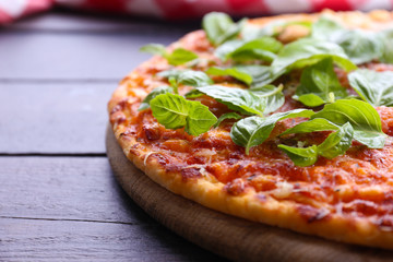 Pizza with basil on wooden table, closeup