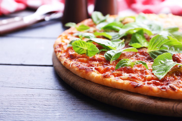 Pizza with basil on wooden table, closeup