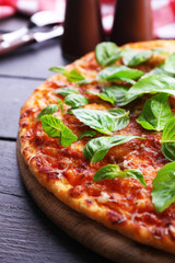 Pizza with basil on wooden table, closeup