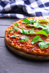 Pizza with basil on wooden table, closeup